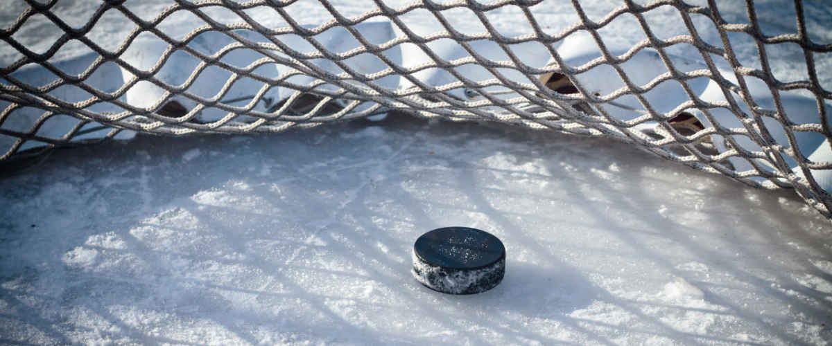 A puck sitting on the ice inside the net